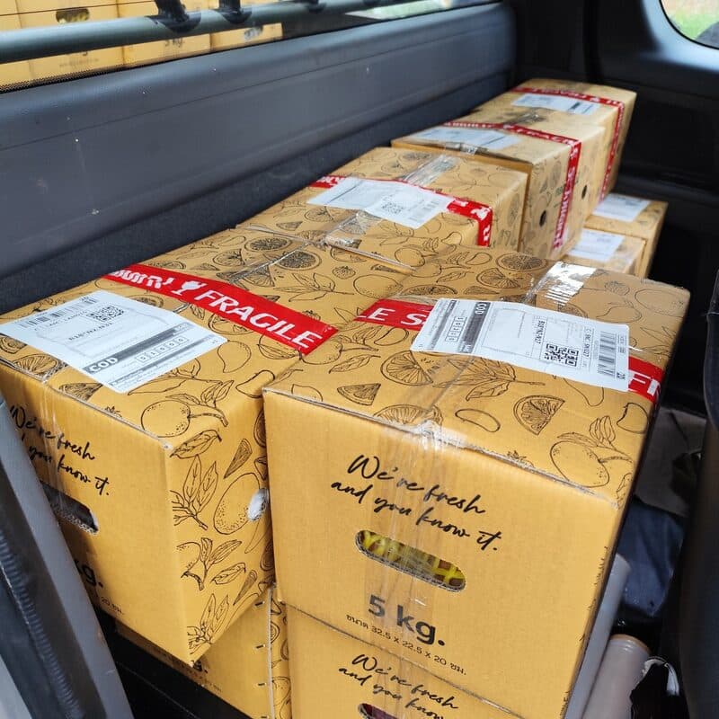 กล่องผลไม้ 5 กก. ติดใบปะหน้าเรียงพร้อมส่งอยู่ในรถของสวน